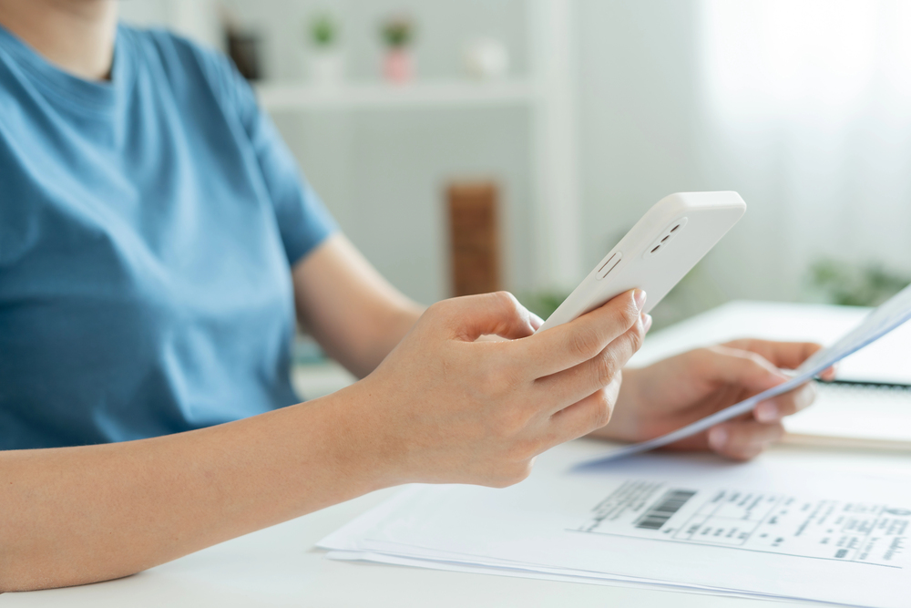 Woman using smartphone to pay utility bills online in China.