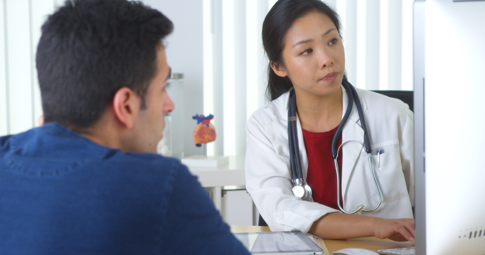 Doctor entering patient information into a computer during a medical consultation.