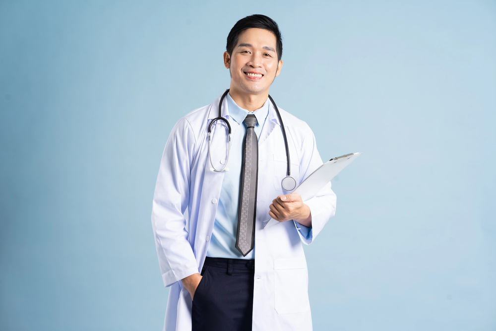 Doctor standing with a stethoscope around the neck, holding a medical report.